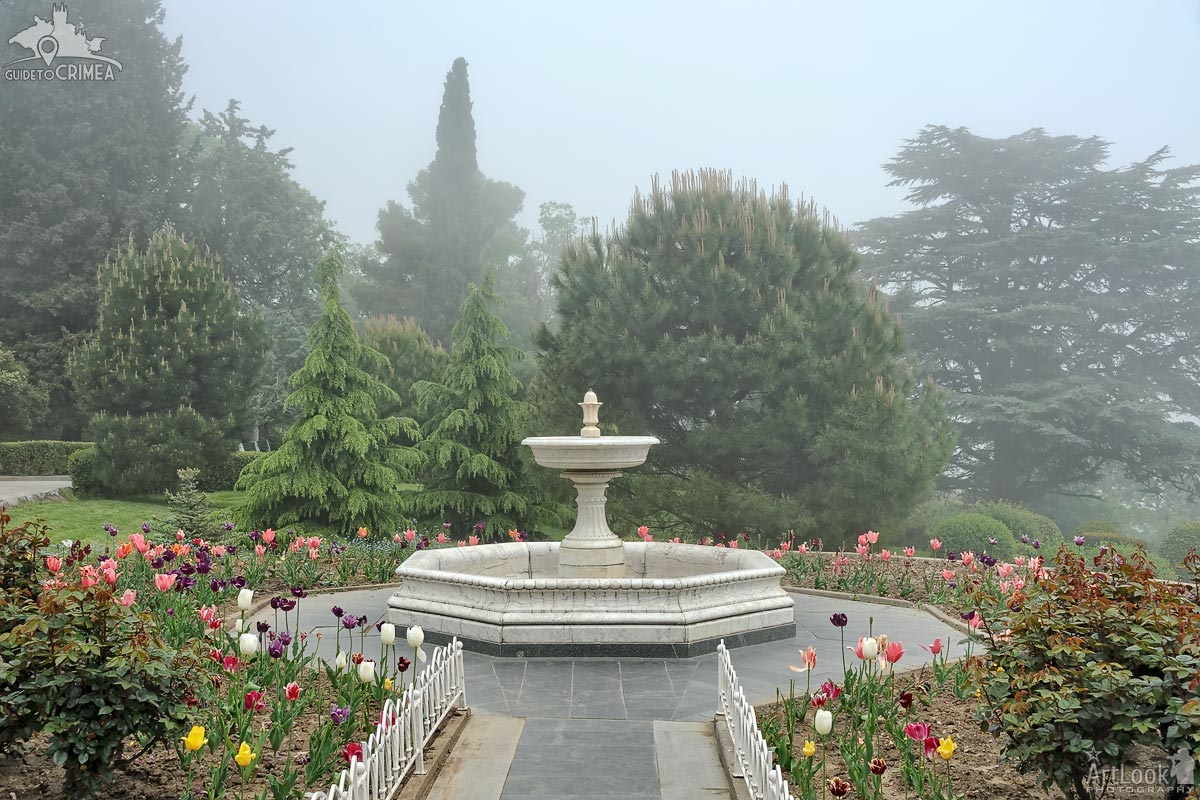 White Marble Fountain with Tulips Flowerbed in the Fog
